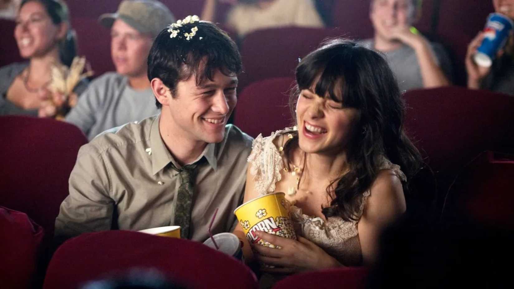Casal ri enquanto come pipoca no cinema em (500) Dias com Ela