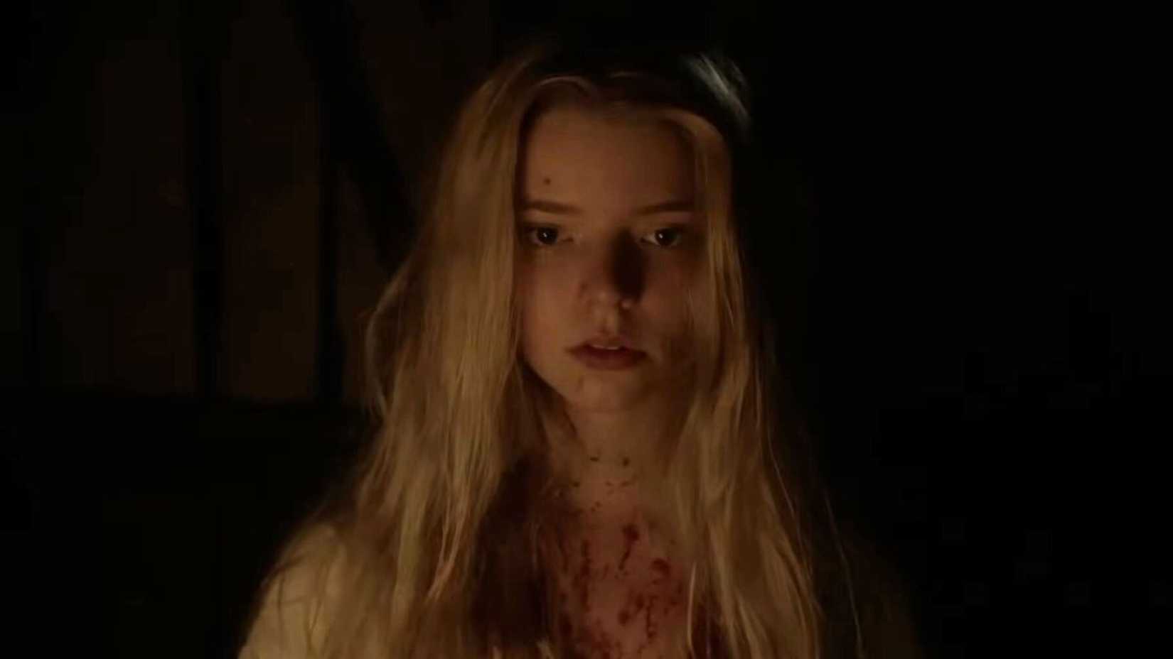 Anya Taylor-Joy como Thomasin, coberta de sangue, conversa com Black Phillip em A Bruxa