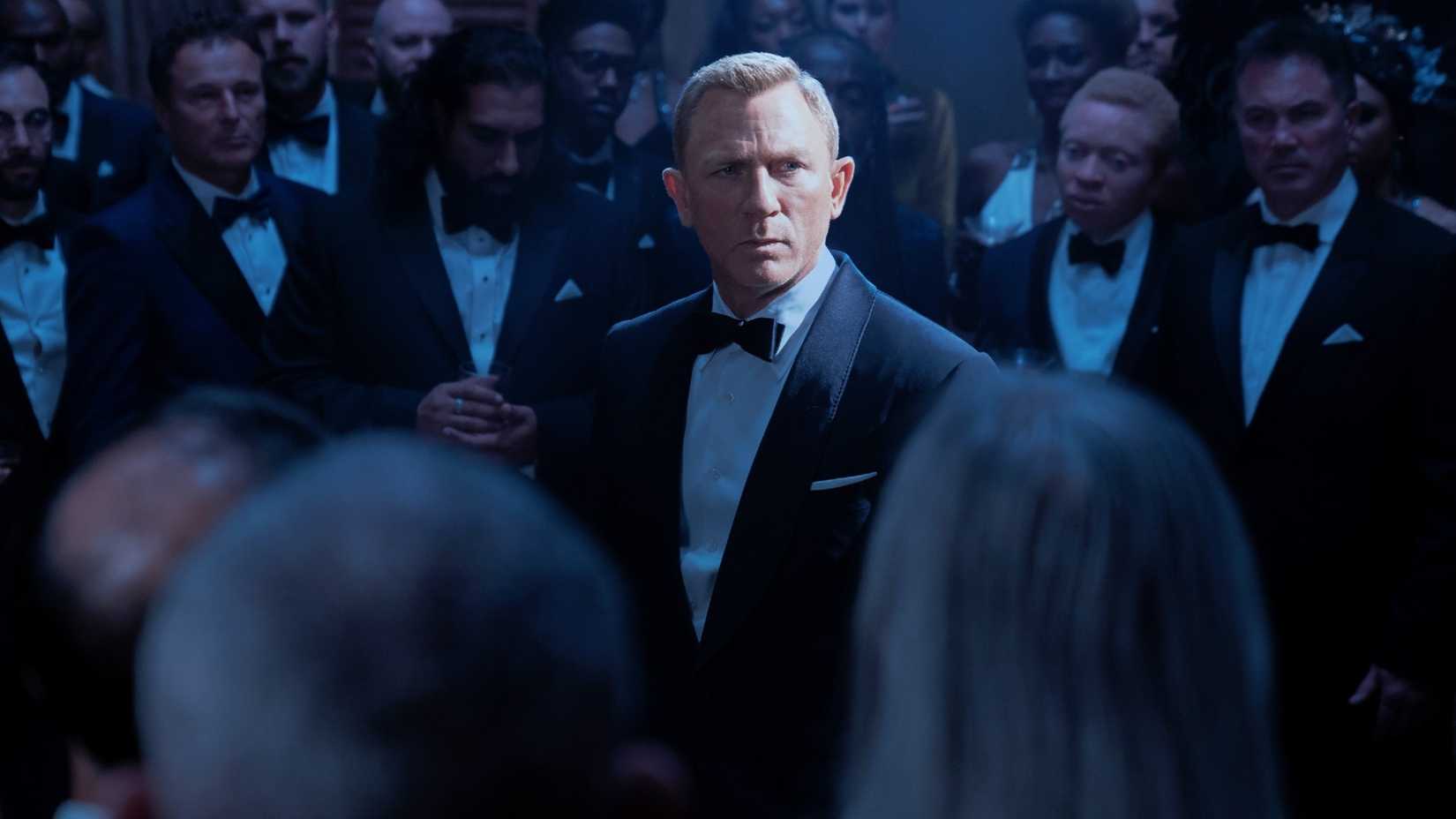 Daniel Craig como James Bond em sala com homens de terno