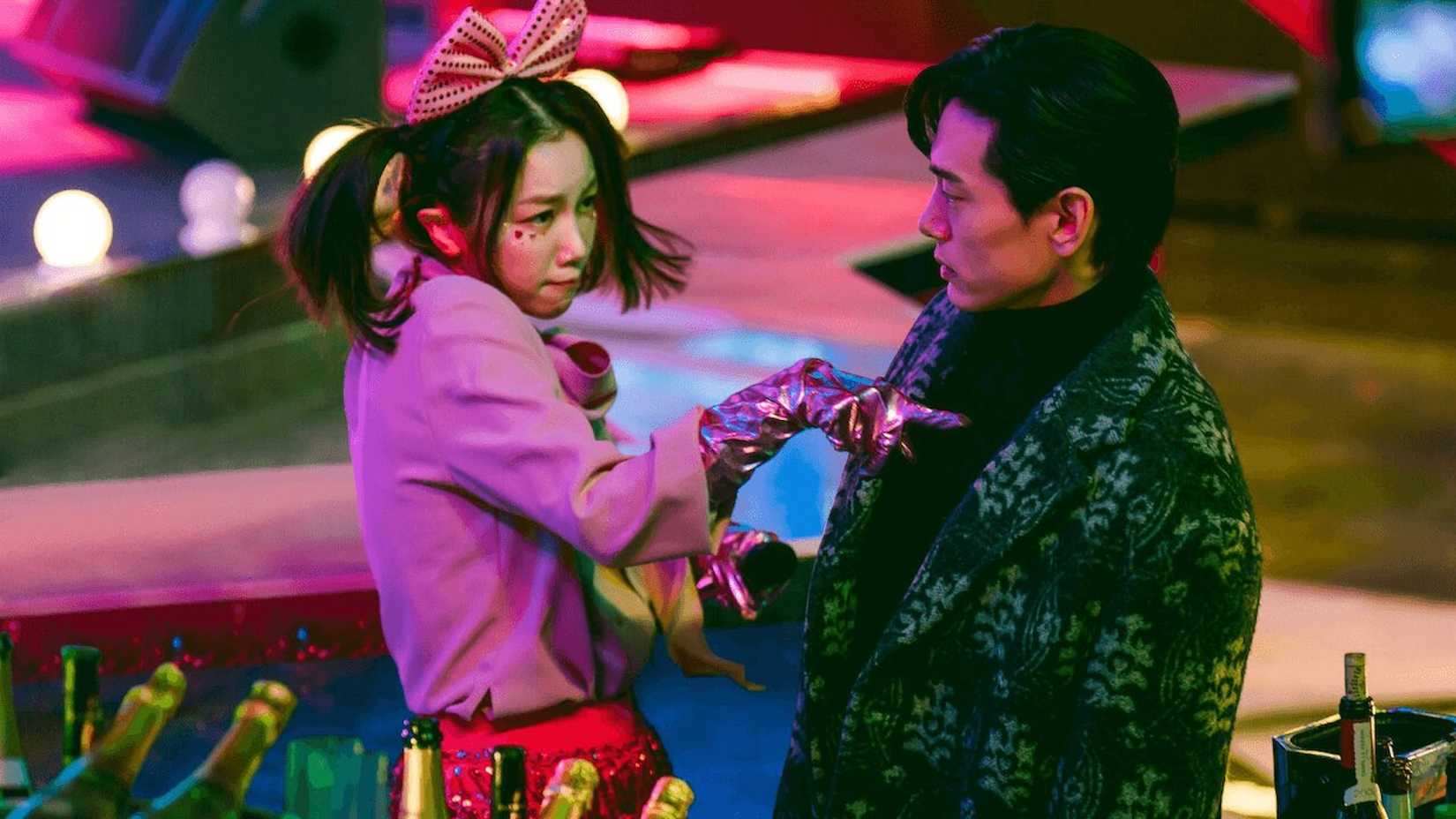 Mulher fantasiada de karaokê cutuca homem atônito em cena da série "Love to Hate You"