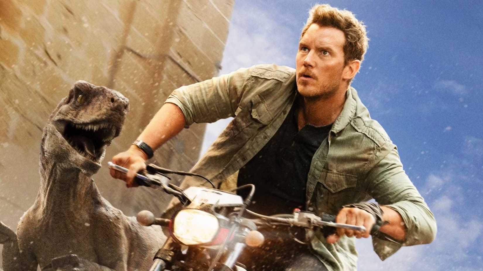 Owen Grady pilota uma moto ao lado de um atrociraptor em Jurassic World: Domínio