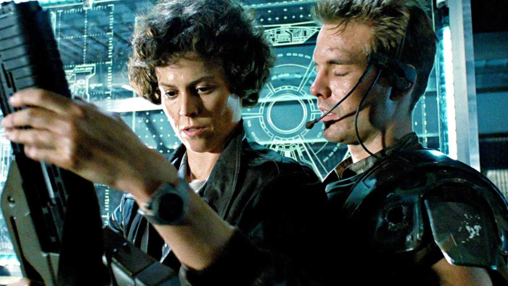 Ripley observa seu blaster enquanto conversa com Hicks em Aliens