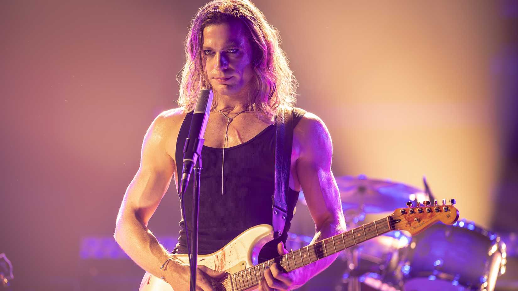 Sam Reid como Lestat no palco com uma guitarra em The Vampire Lestat