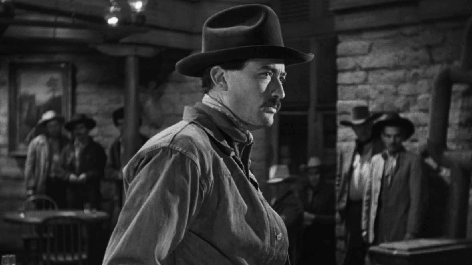 Gregory Peck vira-se lentamente em um bar sob o olhar de homens em "O Pistoleiro"